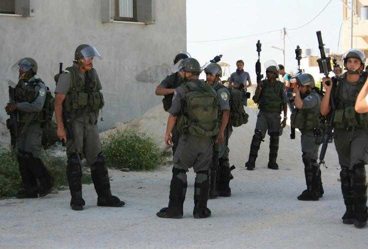Los guardias fronterizos de MAGAV vestidos con armadura y cascos se paran en una esquina. Algunos tienen sus armas a su lado y otros los tienen apuntando hacia arriba en el aire.