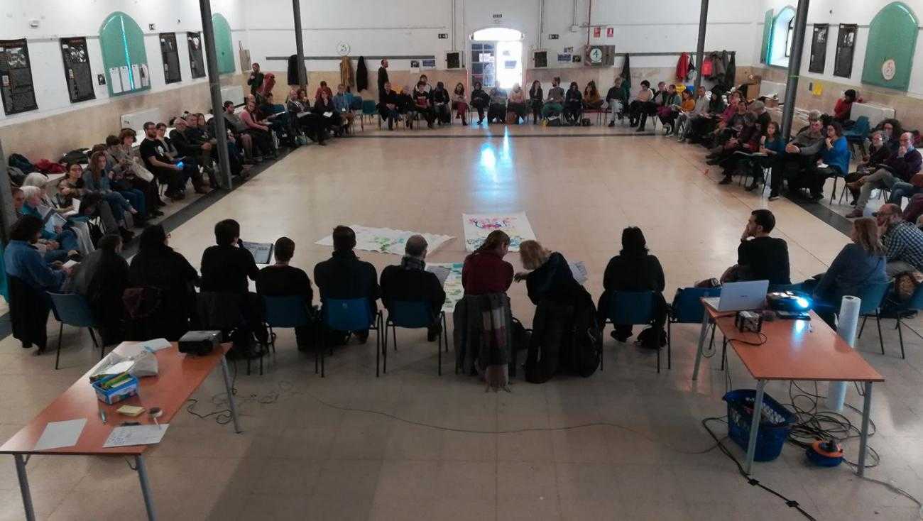 A large group of people sit in a large circle during the Noviolencia2018 congress