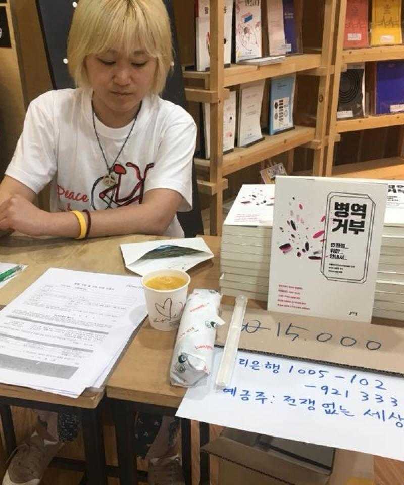 Person sitting at a table with a stack of books next to them