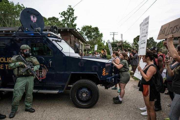 A group of protesters peacefully block an armoured police van