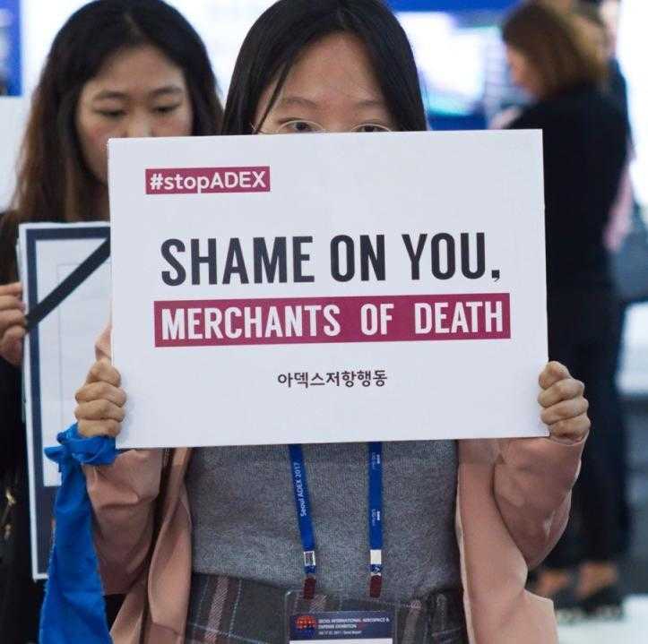 An activist in Seoul holds a "shame on you" banner during the ADEX arms fair