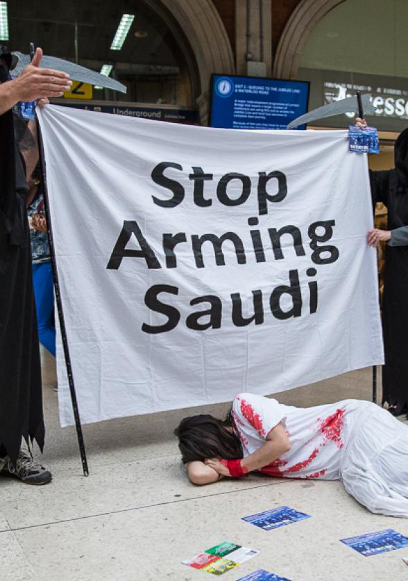 Activists stand with a banner reading "Stop Arming Saudi"