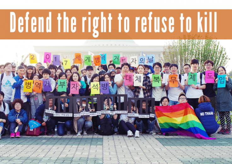 Korean activists holding peace flags, with the text 'Defend the right to refuse to kill' at the top