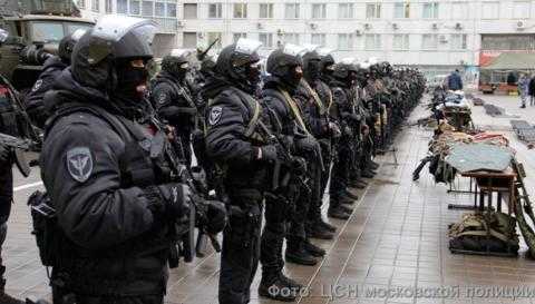 Members of the Russian SOBR stand in formation, dressed in black with helmets, and heavily armed.