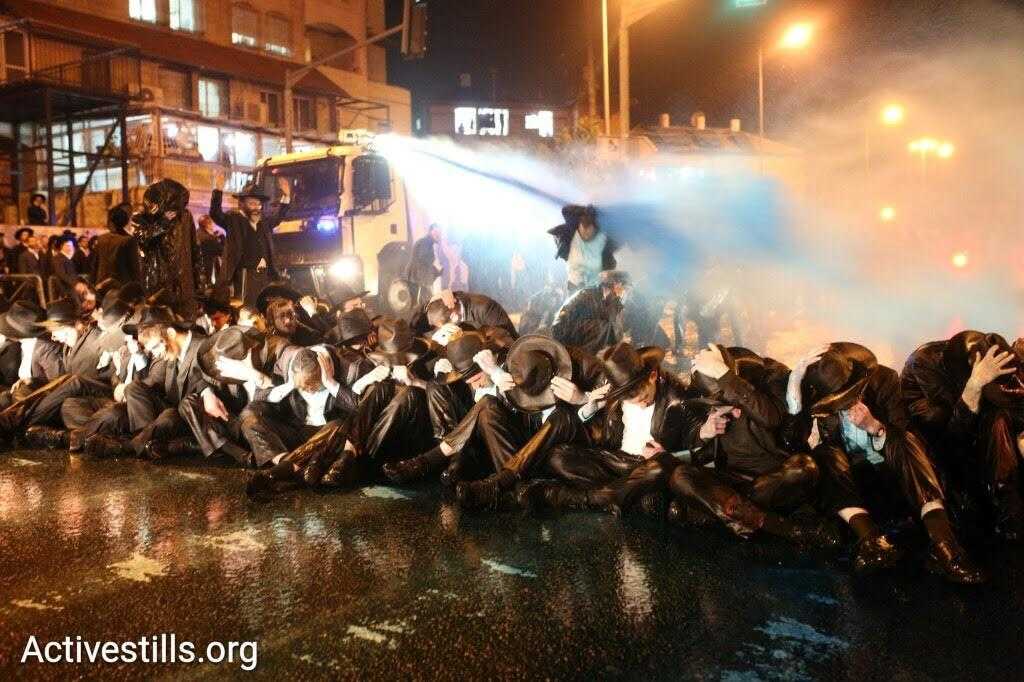 A police van sprays ultra-Orthodox demonstrators with blue liquid during a protest