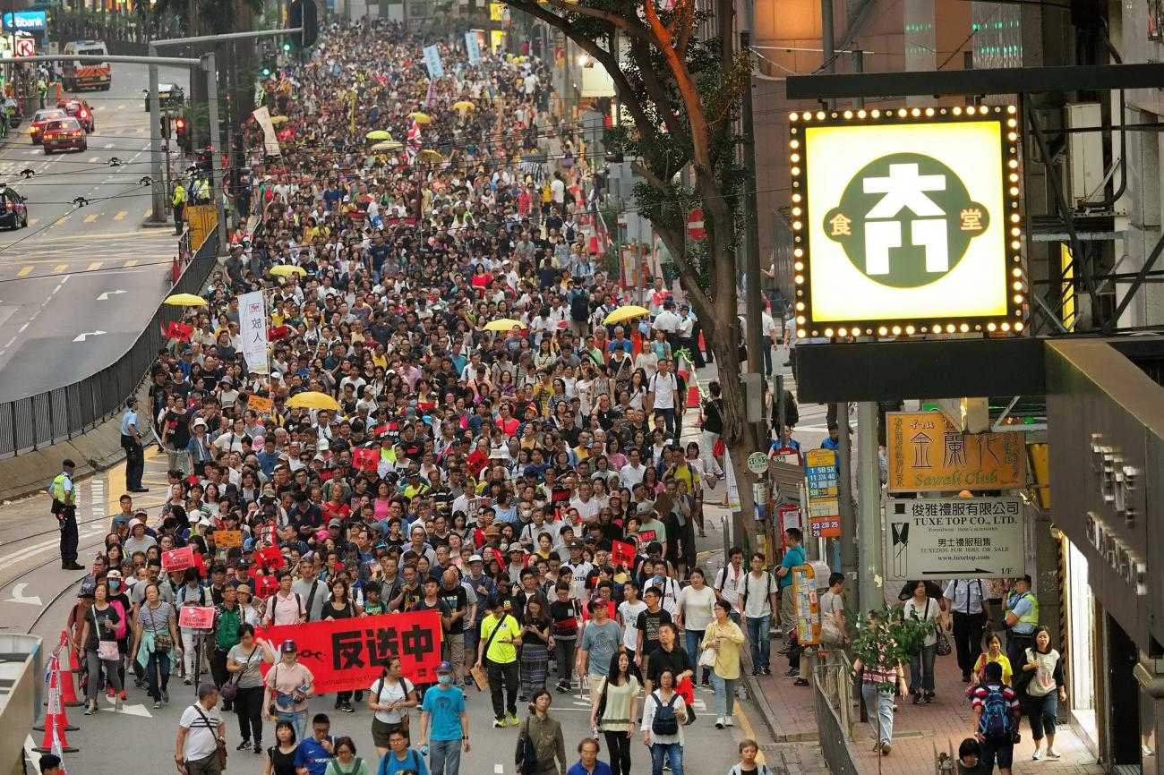 A large number of protesters march down a street 