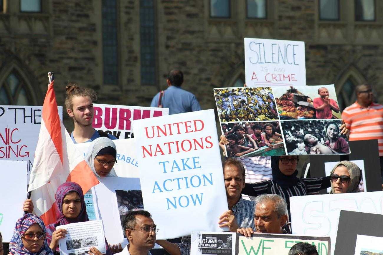 A protest in solidarity with the Rohingya community in 2018. In the middle of a crowd someone is holding a sign saying "United Nations Act Now"