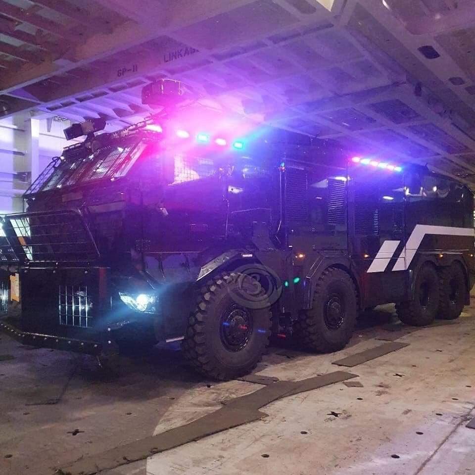 A large water cannon parked up, flashing its lights.