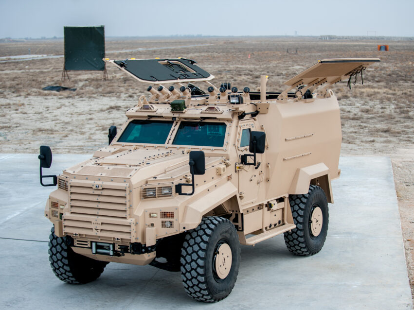 An armoured 4x4 vehicle outide. It is a tan colour.
