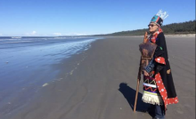 Chief Namoks stood by a river dressed in traditional regalia