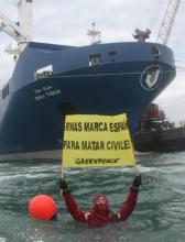 A greenpeace activist in the water in front of a boat, loaded with weapons destined for Saudi Arabia