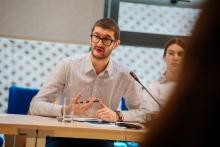 An image of Milan Sekulovic sat behind a table, giving a presentation