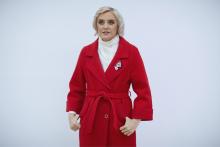 A picture of Olga. She has short blonde hair and is wearing a bright red coat.