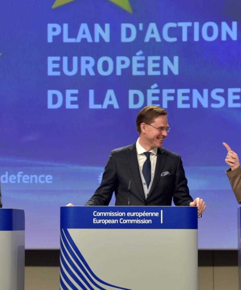 Three politicians stand in front of a sign saying "Plan of Action: European Defence Fund" in French