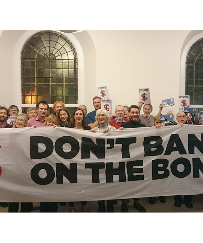 A large number of people standing behind a banner reading "Don't Bank on the Bomb"