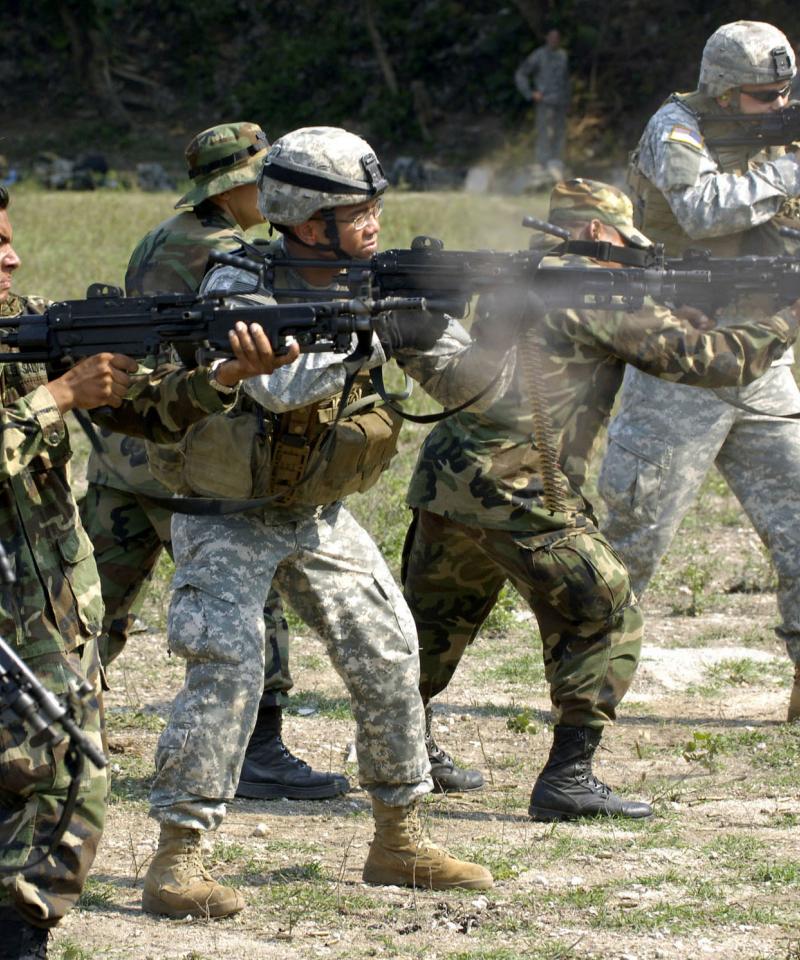 Soldiers from the USA and Mexico stand in a line, firing machine guns