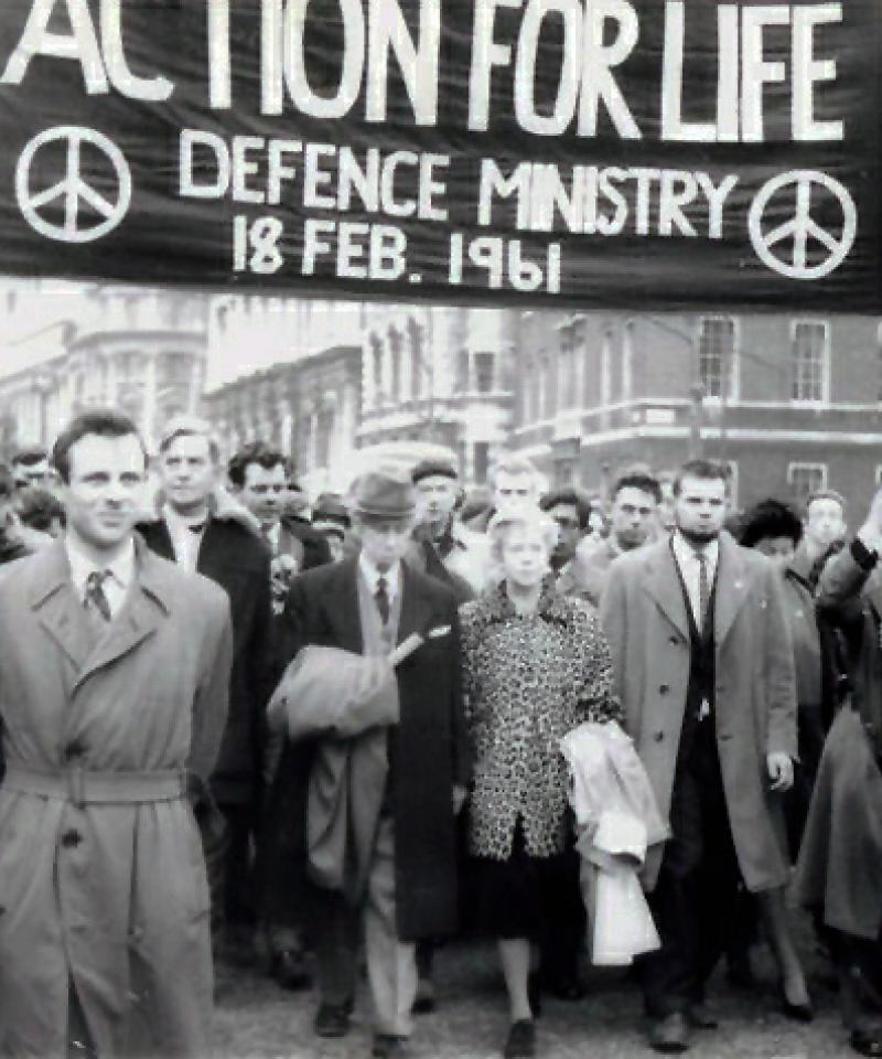 A black and white photo depicting a crowd of people carrying a banner reading "Action for Life"