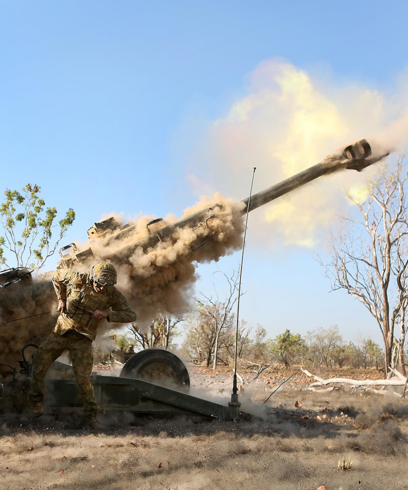 Two soldiers fire a howitzer cannon