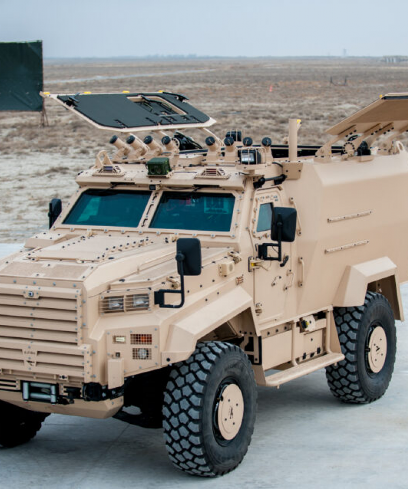 An armoured 4x4 vehicle outide. It is a tan colour.