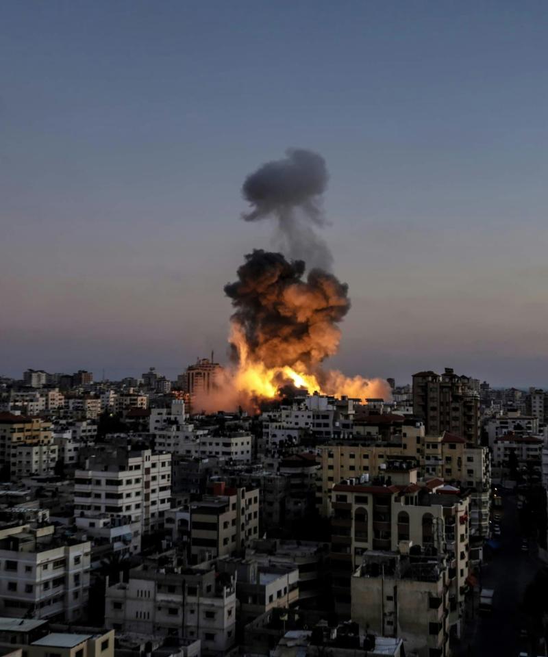 A view of a city at dusk. In the middle a large fireball rises from the sky with smoke above it.