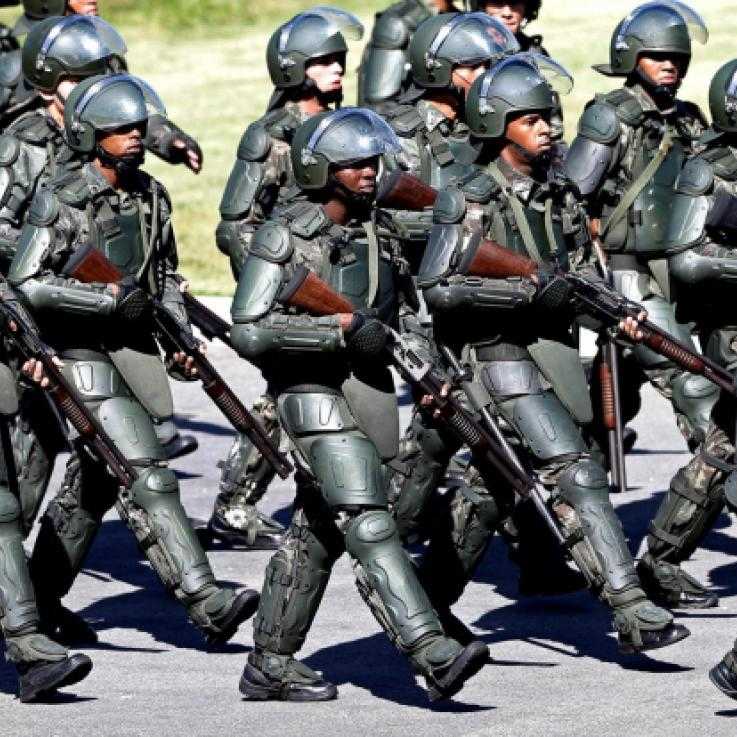 A large group of heavily armed and armoured police in Brazil during the world cup, march in formation.