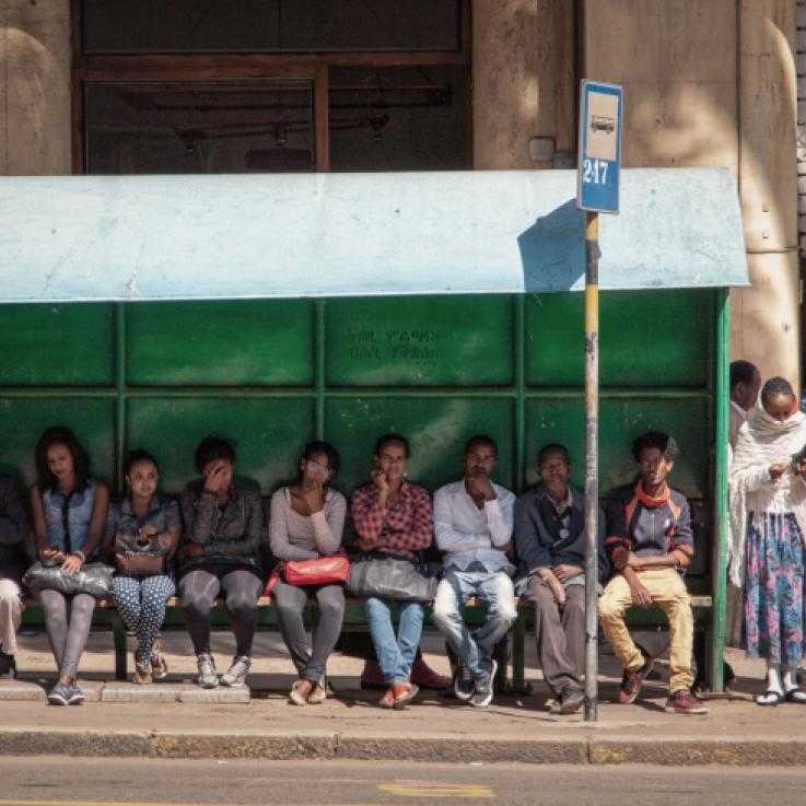 Gente sentada esperando en una parada de autobús