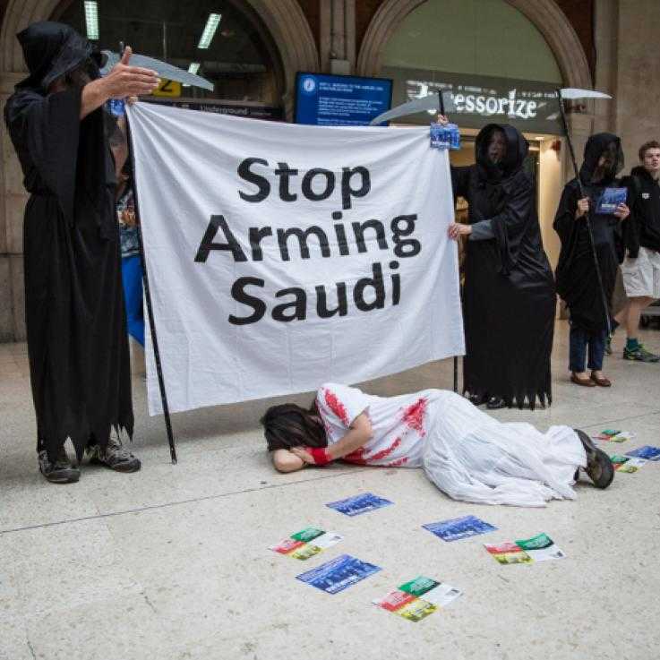 Activists dress in black "grim reaper" outfits and hold a banner reading "Stop Arming Saudi"