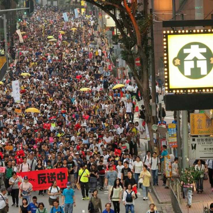 A large number of protesters march down a street 