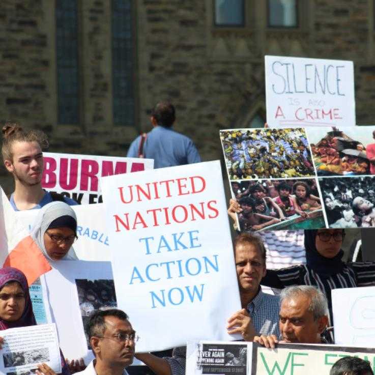 A protest in solidarity with the Rohingya community in 2018. In the middle of a crowd someone is holding a sign saying "United Nations Act Now"