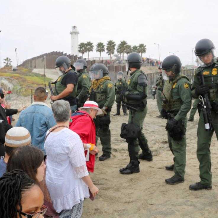 Los líderes religiosos intentan llevar a cabo una ceremonia de agua pidiendo que la paz con justicia regrese a la tierra mientras los agentes de la Patrulla Fronteriza de los Estados Unidos observan