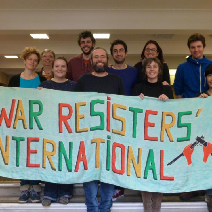 A group of people holding a banner that says War Resisters International