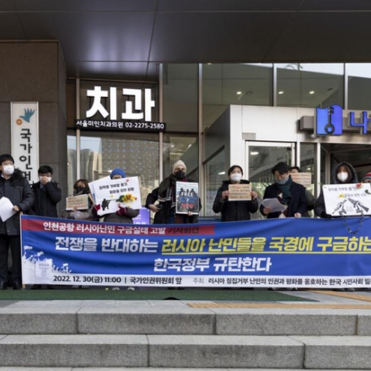 Personas sosteniendo una pancarta frente a un aeropuerto